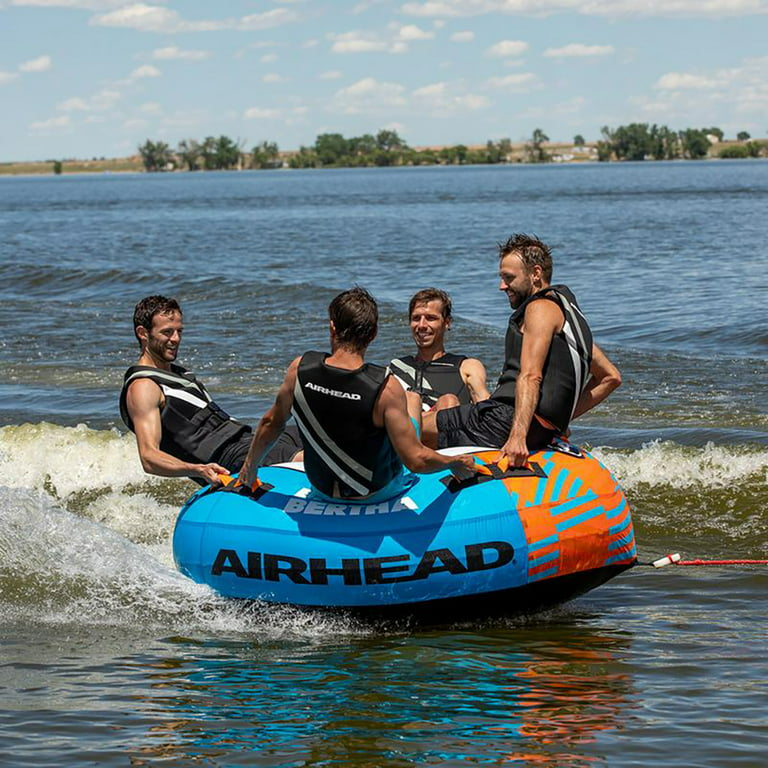 Men enjoying water sports while wearing Airhead Neolite Orca Xs personal flotation devices, sitting on an Airhead inflatable tube.