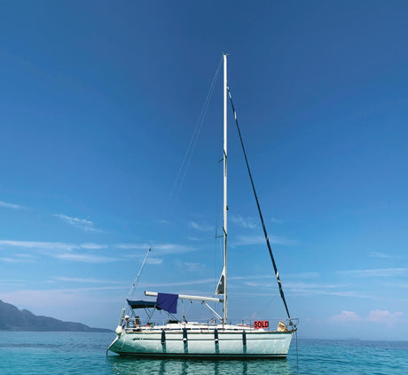 Sailboat anchored on calm waters with a clear blue sky backdrop.